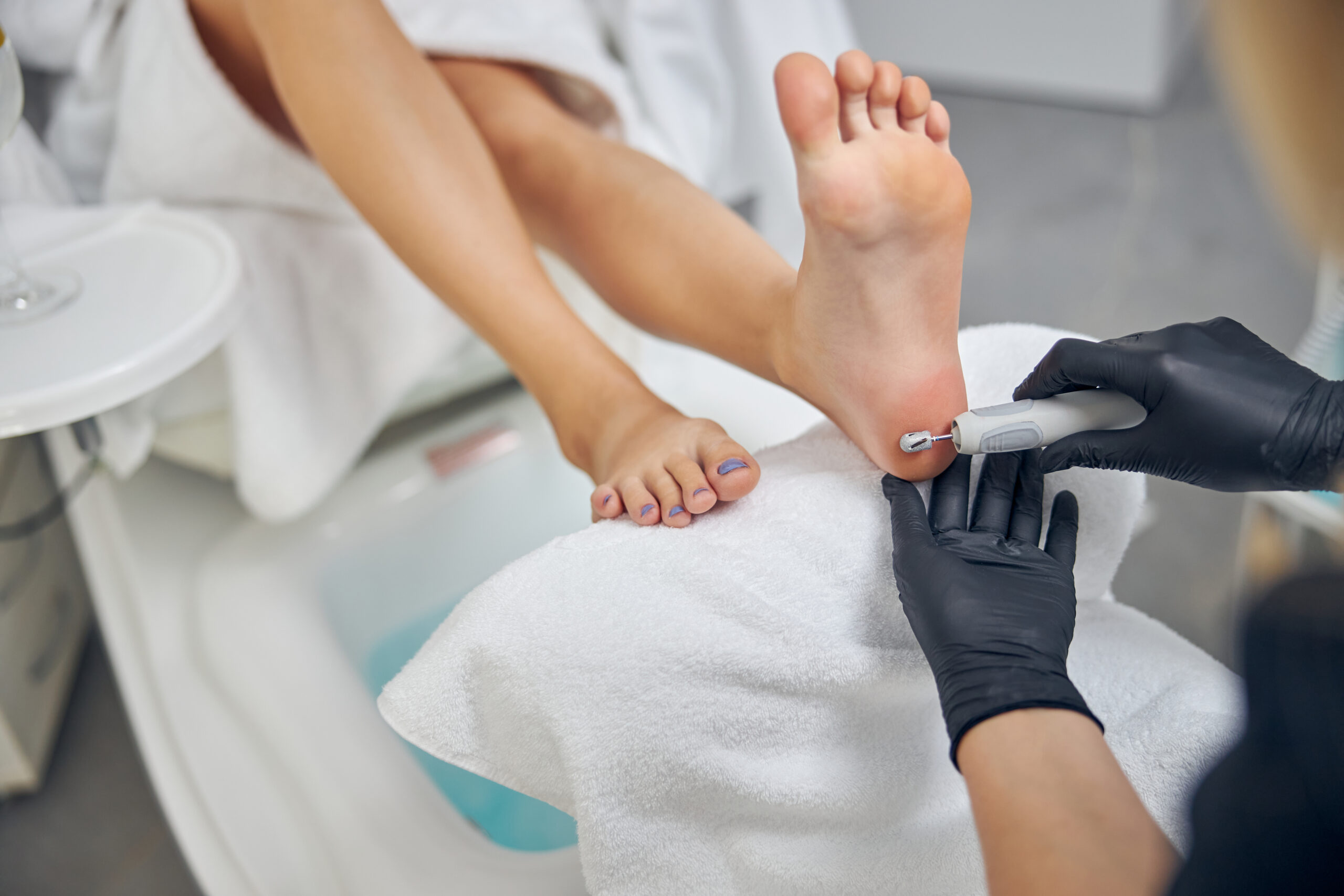 top-view-close-up-female-foot-while-nail-artist-is-taking-care-sole-skin-with-digital-peeling-machine